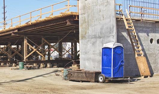 a row of modern porta potties at a busy job site, designed for easy use and maintenance